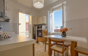 A compact kitchen with a white countertop, a microwave, a refrigerator, and a dining area with a table and chairs.