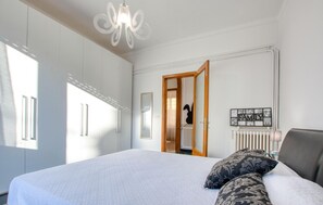A bedroom with a large bed, a chandelier, a radiator, and a 'FAMILY' sign on the wall.