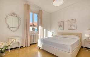 A bedroom with a large bed, a dresser, a mirror, and two framed pictures on the wall.