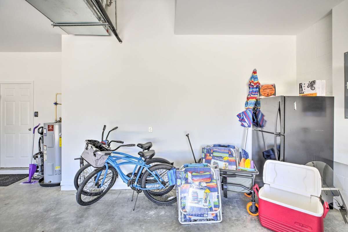 Un garaje con una bicicleta azul, un enfriador rojo y un carro con varios objetos.
