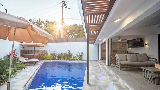 A swimming pool with a tiled deck, outdoor furniture, and umbrellas. - Spacious House Pool & Jacuzzi (Xochitepec)