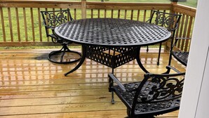 A wooden deck with a round table and chairs, surrounded by a wooden railing.
