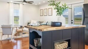 Una cocina moderna con una isla de madera, un ventilador de techo y un ventanal con vistas.
