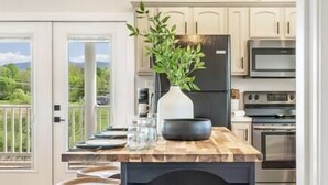 Una cocina moderna con una isla de madera, electrodomésticos de acero inoxidable y vistas al exterior.