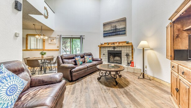 A spacious living room with a leather sofa, a round coffee table, and a fireplace. - Relaxing Ruidoso Retreat: Walk to Midtown! (Ruidoso)