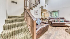 A spacious living area with a staircase, a leather sofa set, and a dining area. - Relaxing Ruidoso Retreat: Walk to Midtown! (Ruidoso)
