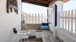 A cozy outdoor seating area with a table and chairs, a bench with cushions, and a decorative wall piece. - Exceptional house near Colares (Colares)
