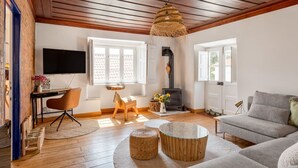 A cozy living room with a fireplace, wooden flooring, a sofa, a TV, and a desk with a chair. - Exceptional house near Colares (Colares)