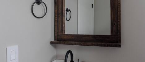 Een badkamer met een wit wastafelmeubel, een donkere kast en een wit toilet.