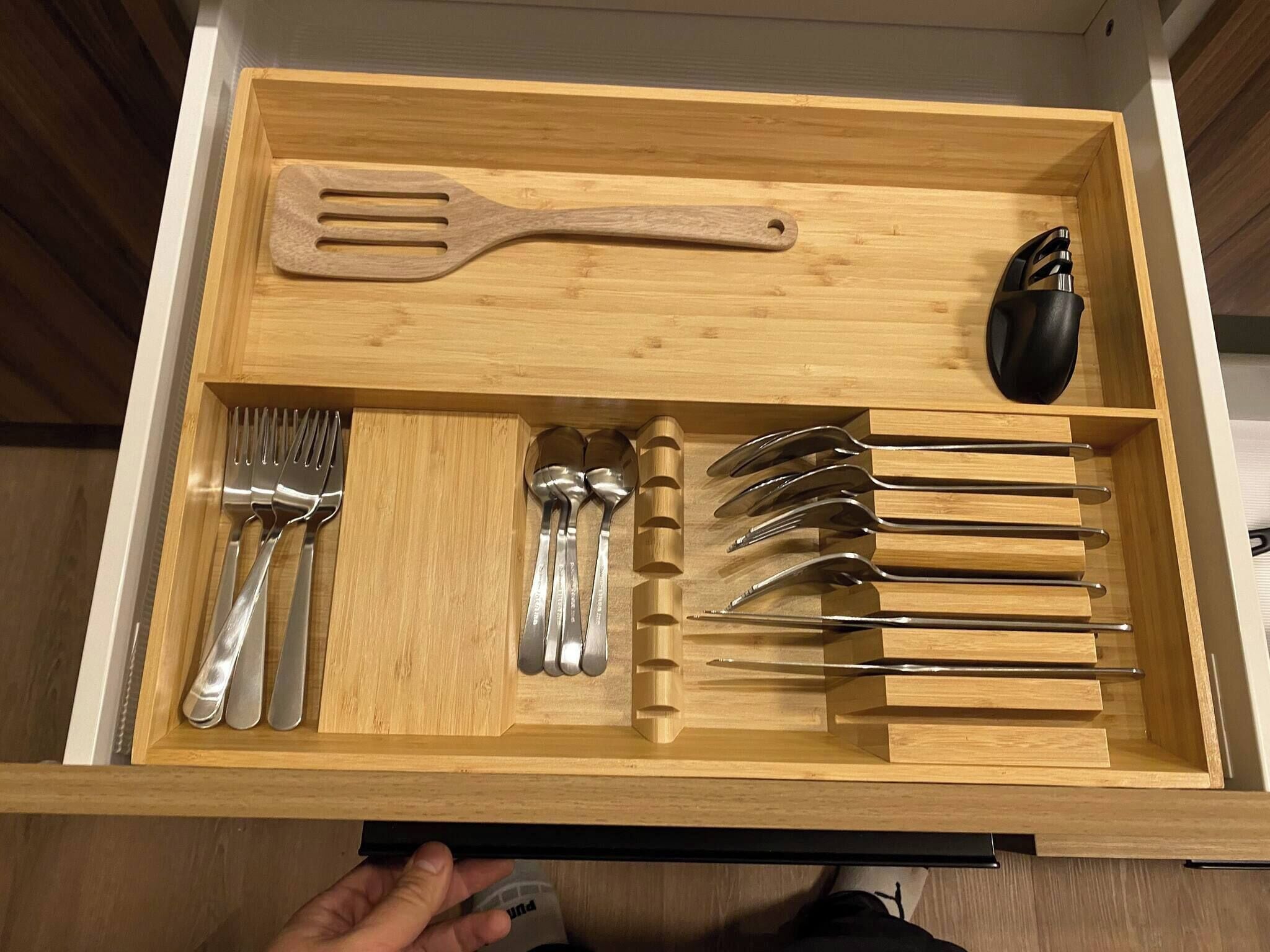 Un cajón con utensilios de cocina, incluyendo tenedores, cucharas y una espátula.