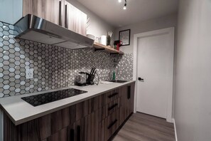 Una cucina moderna con schienale in piastrelle esagonali, mobili in legno, cappa aspirante in acciaio inossidabile e lavastoviglie integrata.