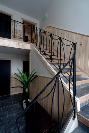 A staircase with a black metal railing, wooden steps, and a potted plant at the bottom. - Guest Suite Close To Whtye Ave (Edmonton)