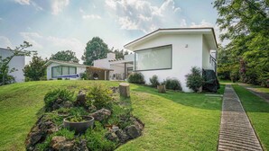 Ein modernes Haus mit gepflegtem Rasen, einem Stein-Element und einem Weg zum Eingang.