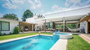 Ein modernes Haus mit Swimmingpool, Sitzgelegenheiten im Freien und einer Hängematte.