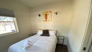 Una habitación de hotel con cama, ventana, un cuadro y una cabeza de ciervo montada en la pared.