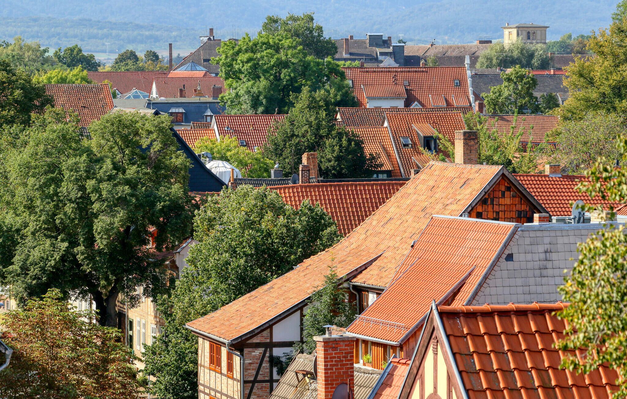 Un quartier résidentiel densément peuplé, caractérisé par ses toits traditionnels recouverts de tuiles rouges, et entouré d’une végétation luxuriante.