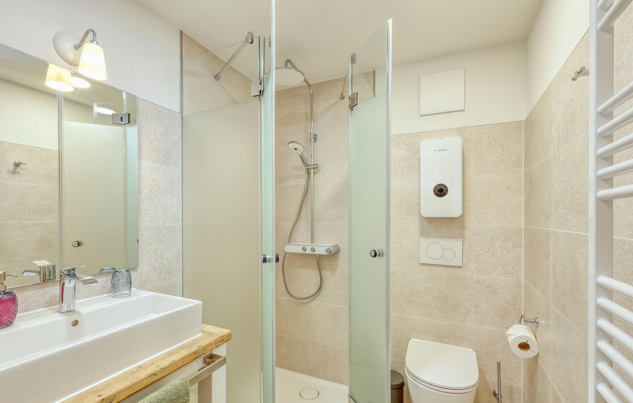 A modern bathroom with a glass-enclosed shower, a sink with a wooden countertop, and a toilet.