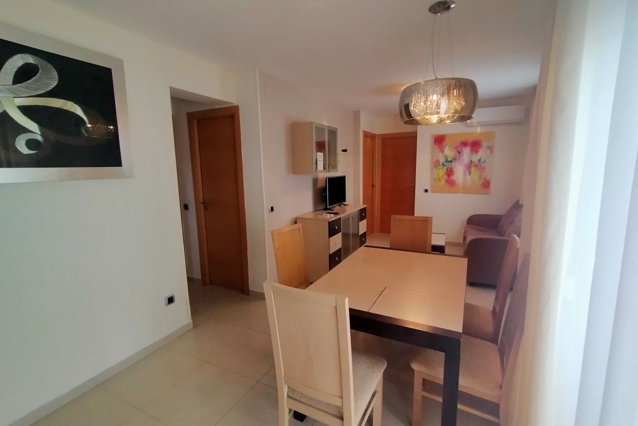 A dining area with a table and chairs, a television, and a cabinet.
