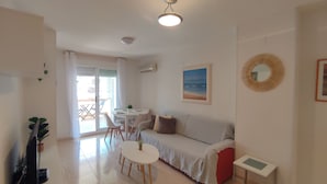 A living room with a sofa, a dining table, and chairs. There is a ceiling fan and a painting on the wall. - ACV - Acapulco IV-1st floor line 4 South (OROPESA)