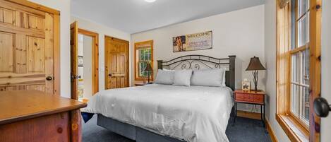 Un dormitorio con una cama grande, un armario de madera y una mesita de noche con lámpara.