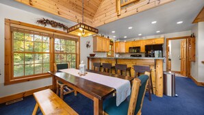 A spacious kitchen with wooden cabinets, a central island, and a dining area with a bench and chairs. - Ski & Golf Spacious Log Cabin in Otsego Resort (Gaylord)