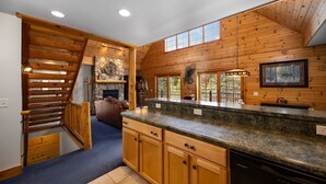A kitchen with wooden cabinetry, granite countertops, and a built-in dishwasher. - Ski & Golf Spacious Log Cabin in Otsego Resort (Gaylord)