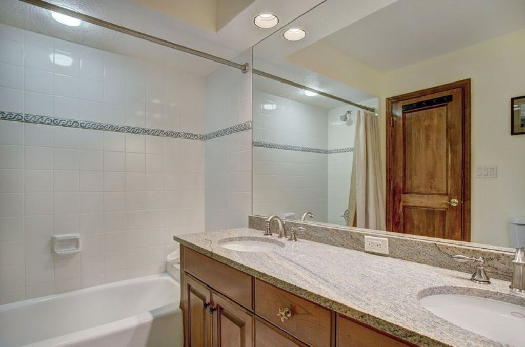 Un baño con dos lavamanos, una bañera y un espejo grande.