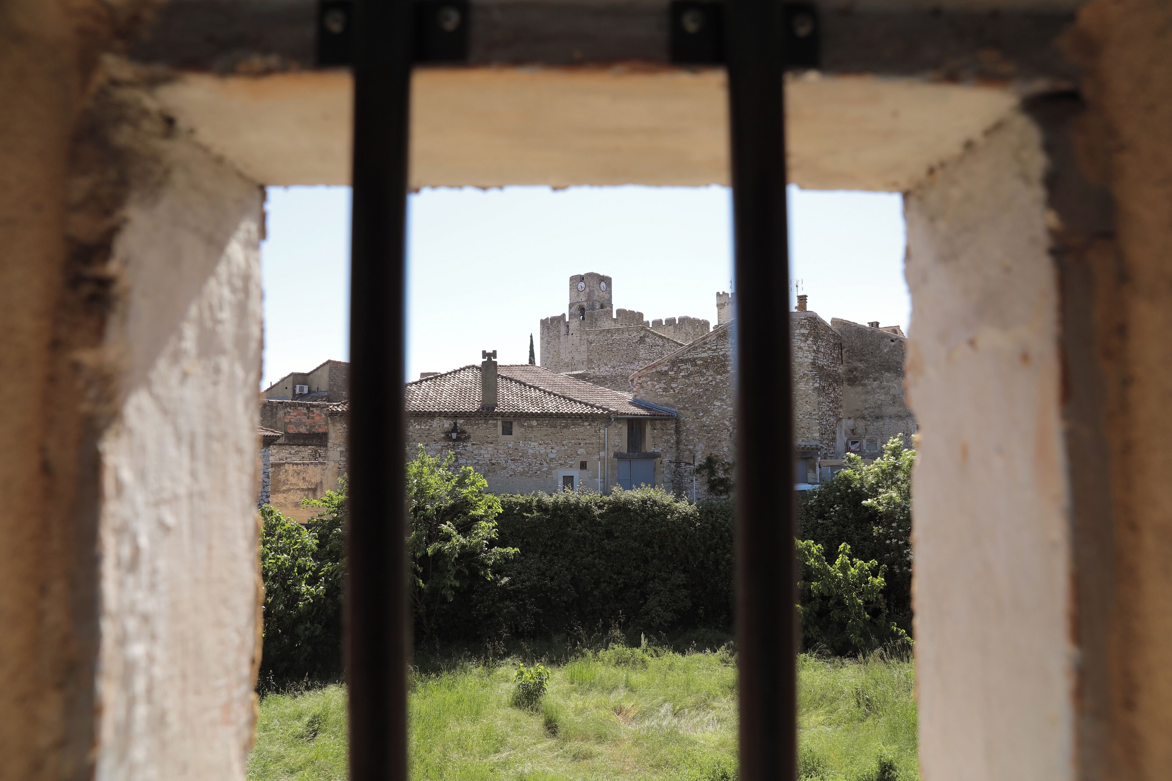 A stone building with a turret, a gate, and a grassy area in the foreground.
