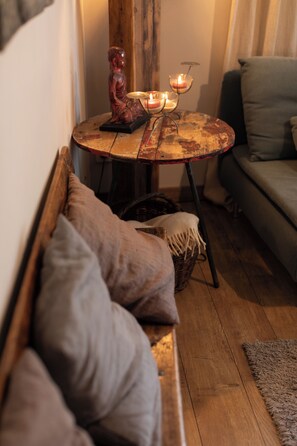 A cozy seating area with a bench, cushions, a small round table with candles, and a wicker basket.