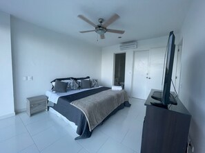 Ein Schlafzimmer mit einem Bett, einem Deckenventilator, einem Fernseher und einem Kleiderschrank.
