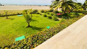 A well-maintained garden with palm trees, a lawn, and a pathway leading to a beach. - Apartamento en Cartagena de Indias, Edificio Morros 3 (Cartagena)