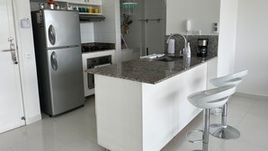 A modern kitchen with a built-in island, stainless steel appliances, and white cabinetry. - Apartamento en Cartagena de Indias, Edificio Morros 3 (Cartagena)