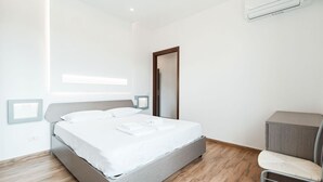 Une chambre moderne comprenant un lit, des tables de chevet, une chaise et un appareil de climatisation.