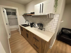 A modern kitchen with a sink, coffee maker, knife block, and cabinets.