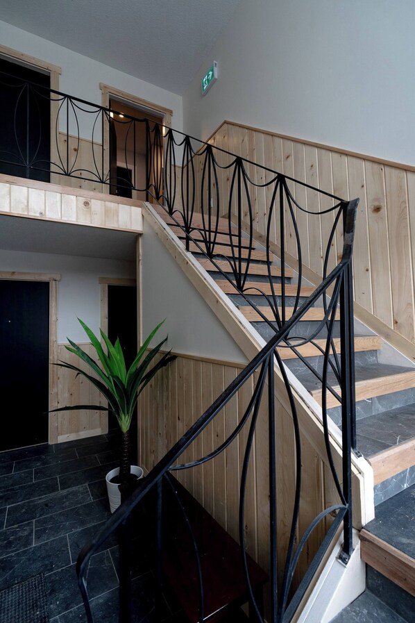A staircase with a black metal railing, wooden steps, and a potted plant at the bottom.