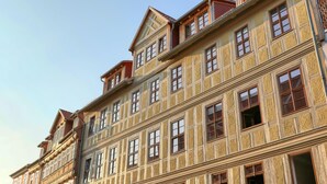 Ein mehrstöckiges Gebäude im traditionellen Baustil, mit einer symmetrischen Fassade, gleichmäßig verteilten Fenstern und dekorativen Elementen.