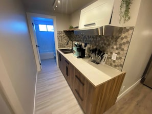 A modern kitchen with a wooden countertop, stainless steel sink, and a hexagonal backsplash. - Brand New Modern Flat 2br1ba Whyte And U (Edmonton)