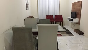 Un comedor moderno con una mesa de vidrio, sillas grises y un sofá rojo.