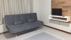 Una sala de estar moderna con un sofá gris, un televisor montado y una pared de acento de madera.
