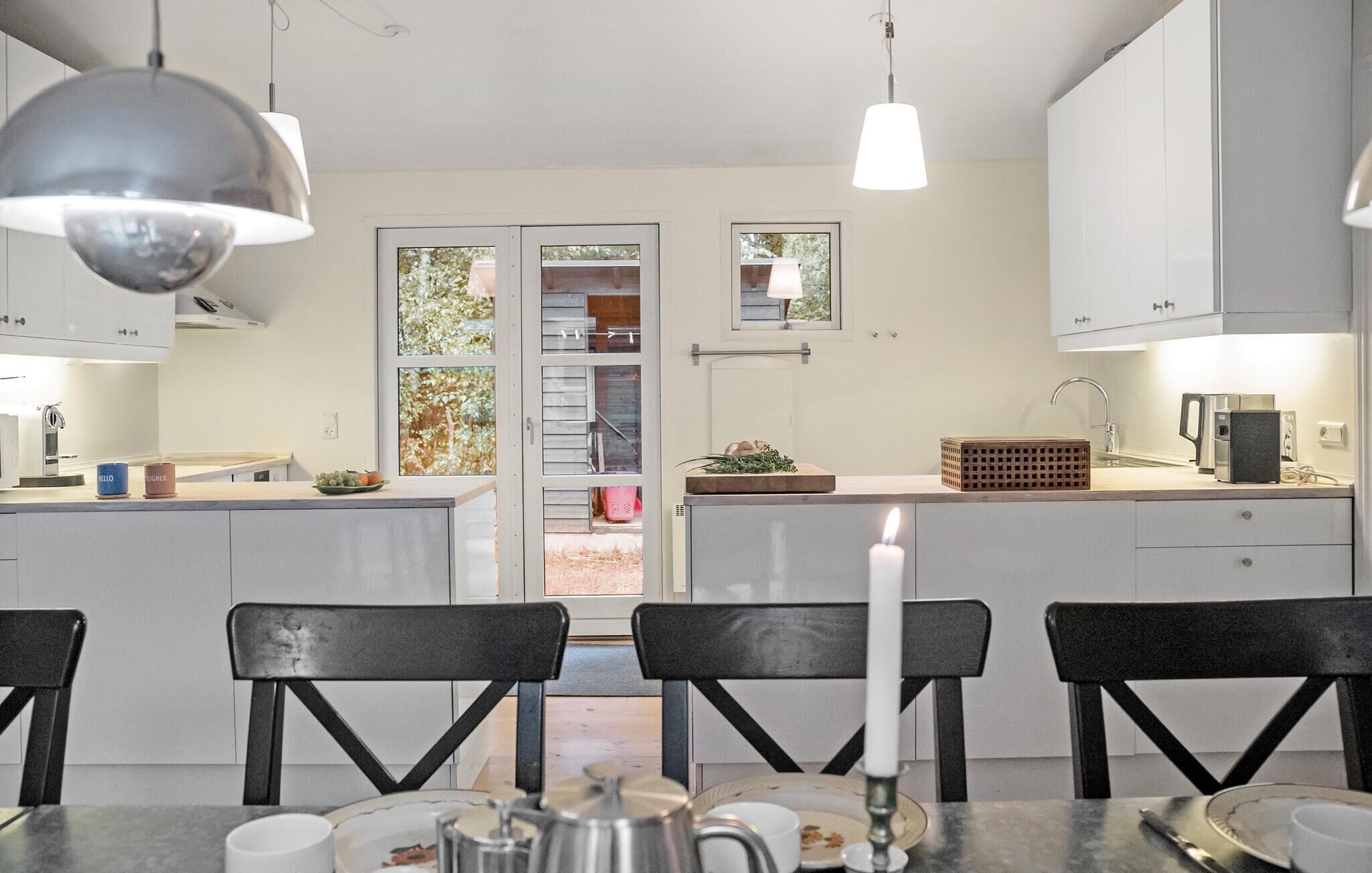 Una cucina moderna con mobili bianchi, un'isola centrale e un'area pranzo con sedie nere.