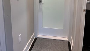 A white door with a frosted glass panel, a light switch, and a doorknob on the wall. - Peaceful and modern retreat (Livingston)