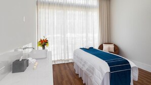 Une chambre d’hôtel moderne avec un grand lit, une baignoire et une coiffeuse avec un miroir.