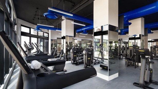Une salle de sport moderne équipée de tapis de course, d’appareils de musculation et de miroirs.