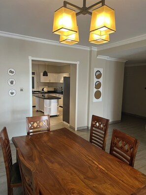 Enjoy meals in this stylish dining area with a dining table and four chairs, accompanied by a chandelier and decorative wall art.