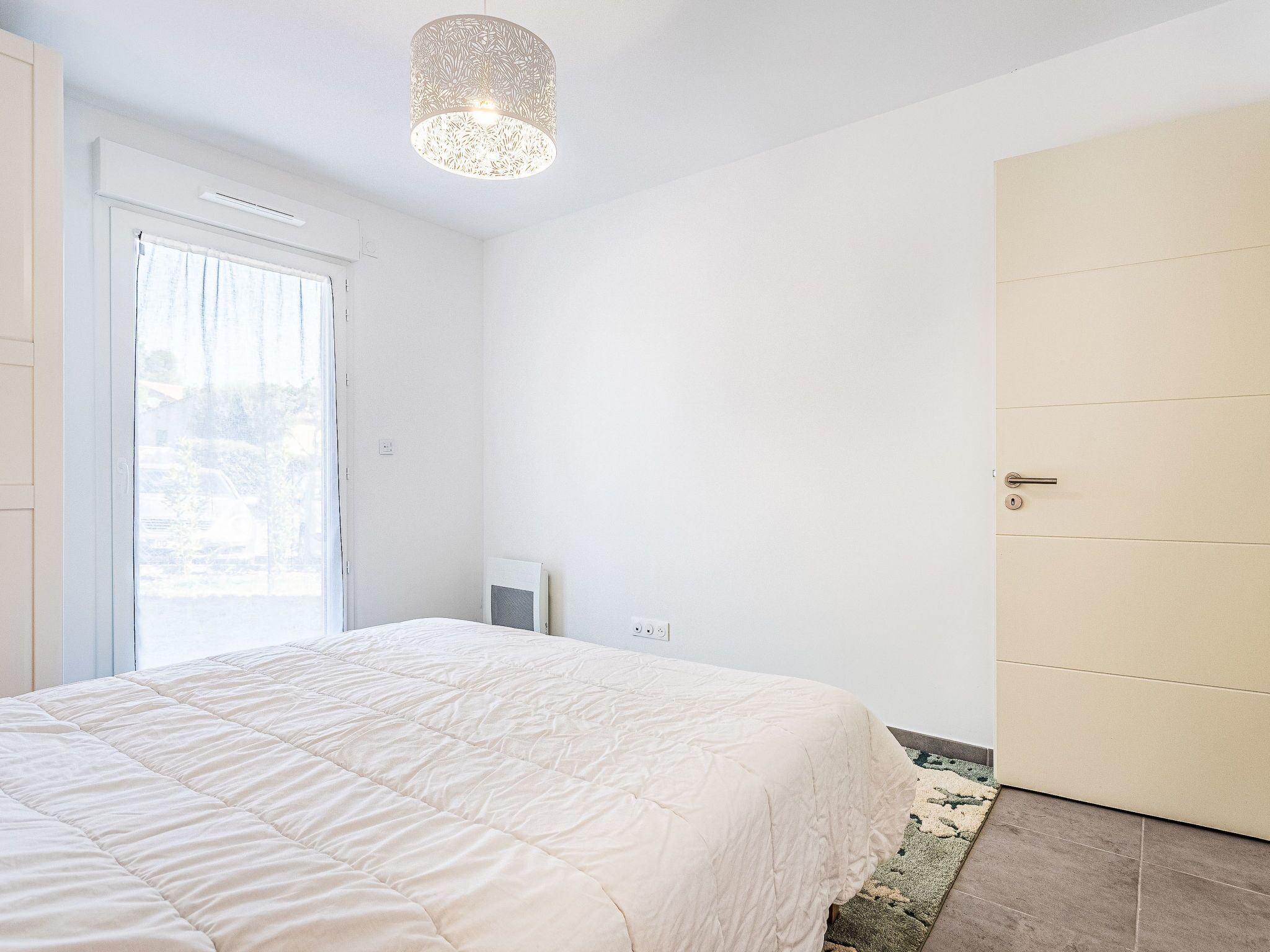Een slaapkamer met een bed, een deur en een raam.