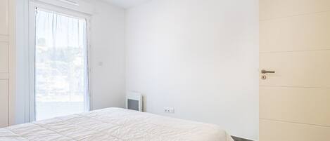 Een slaapkamer met een bed, een deur en een raam.