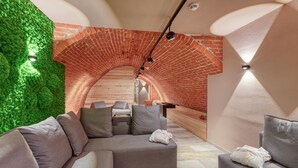 Ein moderner Spa-Bereich mit grüner Wand, Ziegelbogen und grauer Sitzgelegenheit.