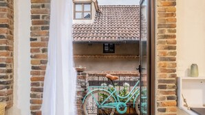 Een deuropening met een wit gordijn, een paar zwarte schoenen en een turquoise fiets op de achtergrond.