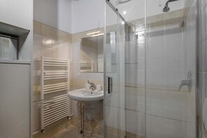 A modern bathroom with a glass-enclosed shower, a white sink, and a towel rack. - San Bernardino 8 - Immobili e Soluzioni Rent (Bergamo)