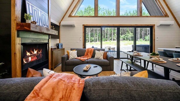 A cozy living room with a fireplace, a large window, and a dining area. - Hot Tub, X Box, Fire Pit, Close 2 Town/Lake Nearby, Pets, TH (Broken Bow)
